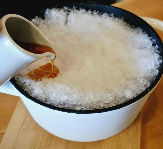 A white mug filled with ice and a dark liquid being poured into it. 1
