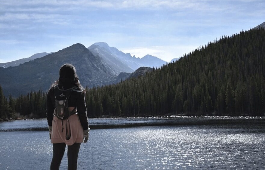 A person standing by a lake with mountains in the background. 4