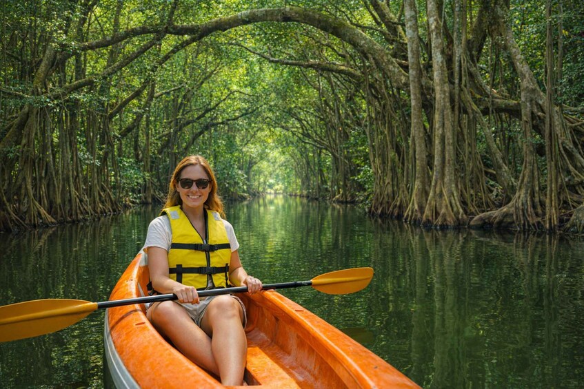 A person in a canoe on a river surrounded by mangrove trees. 1