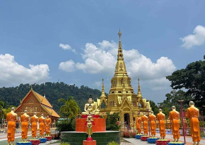 A golden temple with a tall spire, surrounded by statues of monks and a smaller temple structure. 4