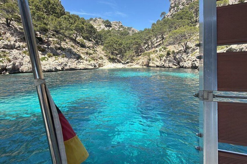 A boat on clear turquoise water with rocky cliffs in the background. 3