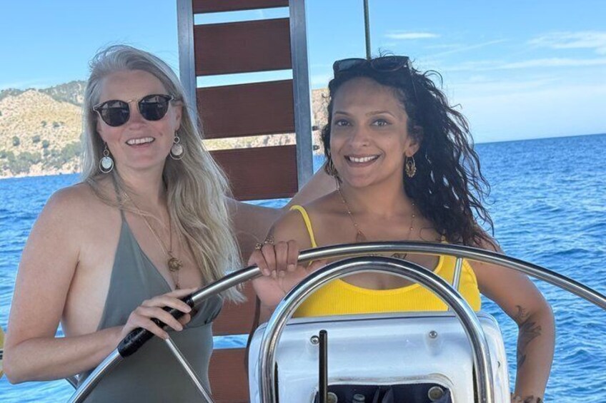 Two people on a boat with a metal railing and a clear blue sky. 2