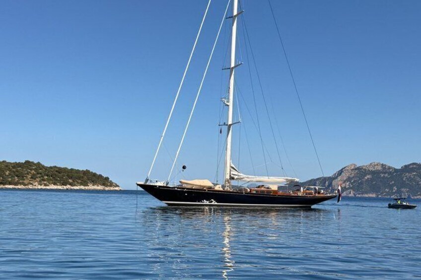 A sailboat on calm waters with a clear sky and a hilly coastline in the background. 5