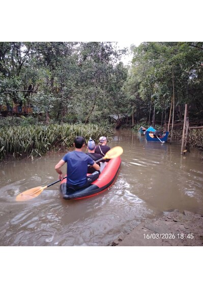 A person paddling a red kayak on a river surrounded by dense vegetation. 1