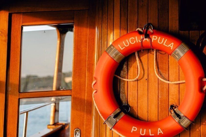 A lifebuoy with 'LUCIA PULA' written on it, hanging on a wooden door. 5