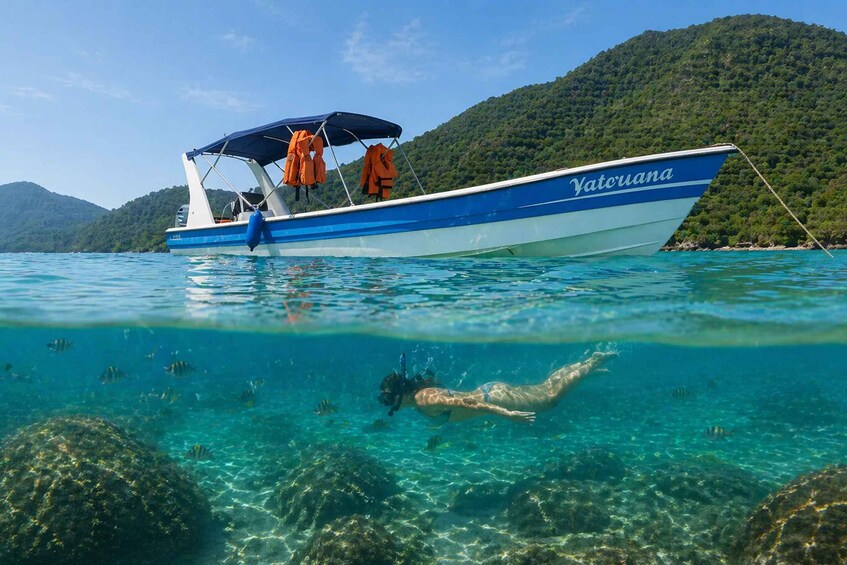 A boat named 'Yatruana' on clear turquoise water with a swimmer in the foreground. 5