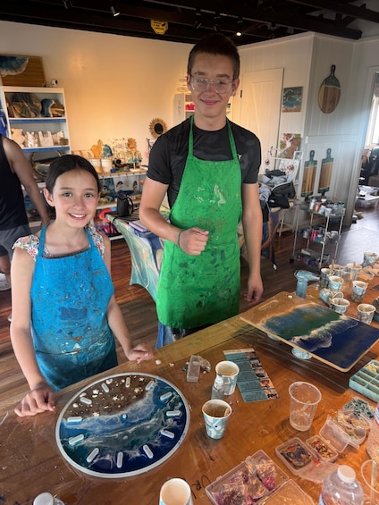 Two people at a crafting table with art supplies and a finished piece of art. 4