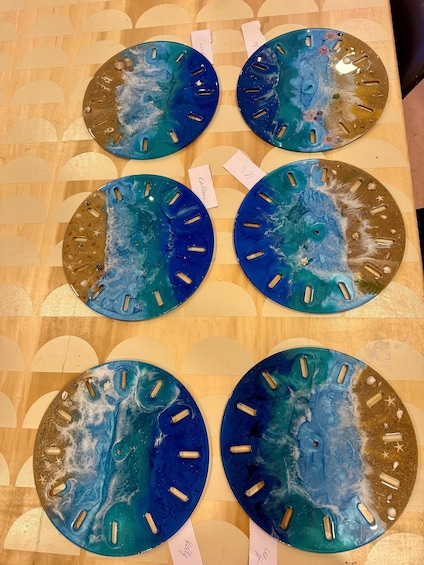 A wooden table with six circular glass art pieces, each with a blue and gold color scheme and starfish decorations. 3