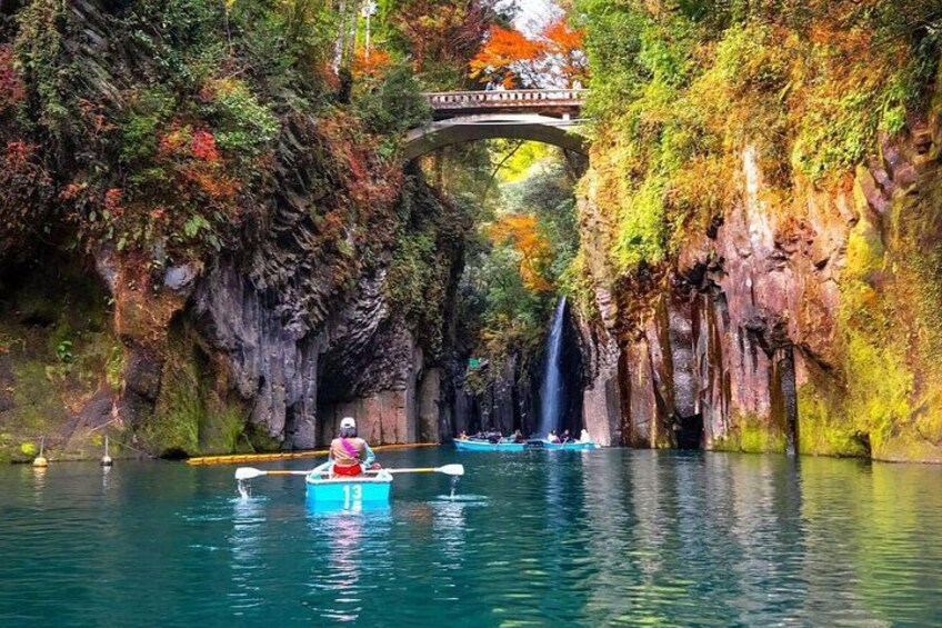 A person kayaking on a river with a bridge and waterfall in the background. 3