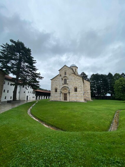 A stone church with a dome, surrounded by a well-maintained lawn and a large tree. 1