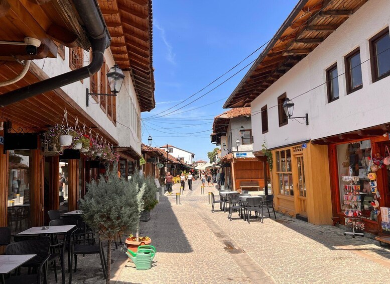A cobblestone street lined with traditional buildings, outdoor seating, and hanging flower baskets. 2