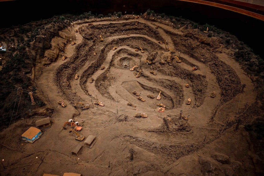 A large, circular, spiral-patterned excavation site with various construction vehicles and equipment. 4