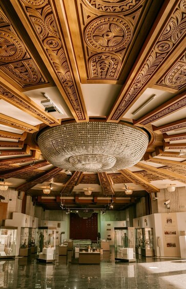 An ornate ceiling with intricate carvings and a large crystal chandelier. 2