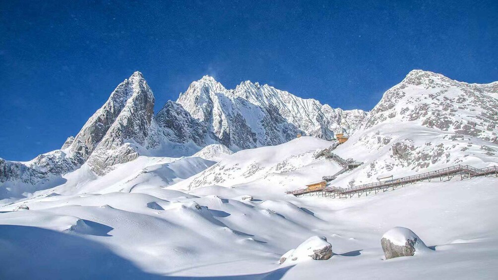 A snow-covered mountain range with a ski lift and a clear blue sky. 3