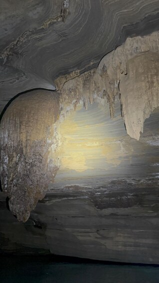 A cave interior with stalactites and a bright light source. 3