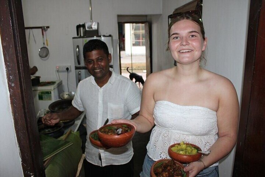 A person holding a bowl of food and another person standing in a kitchen. 5