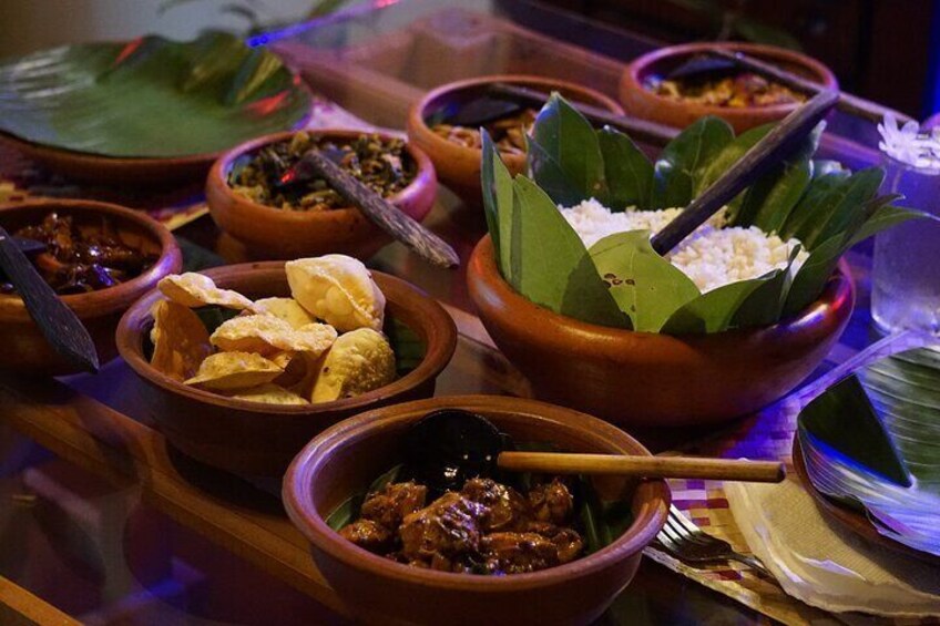 A variety of dishes in clay bowls, some with leaves and a spoon, and a plate with a banana leaf. 3