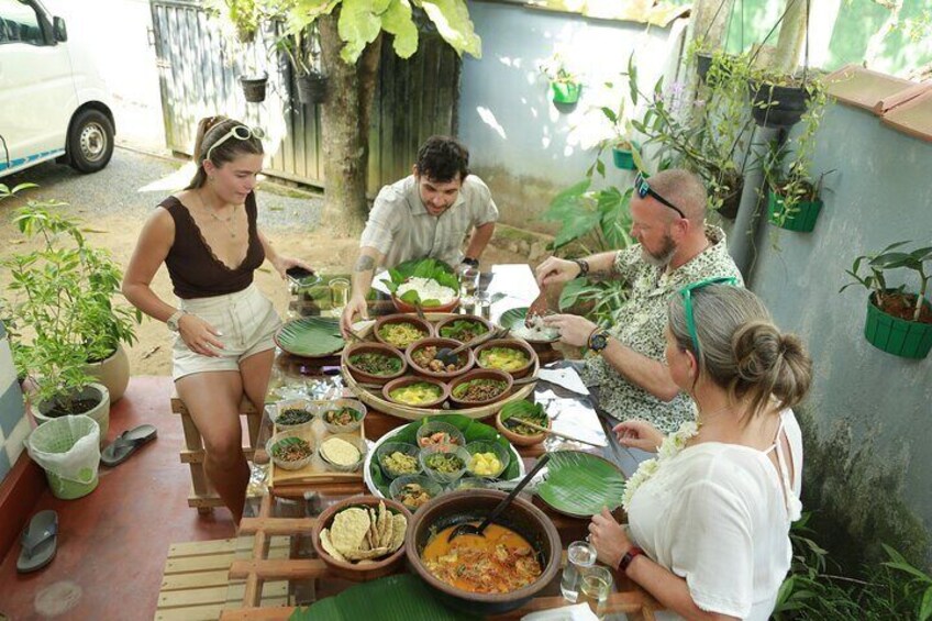 A group of people dining outdoors with various dishes on a table. 2