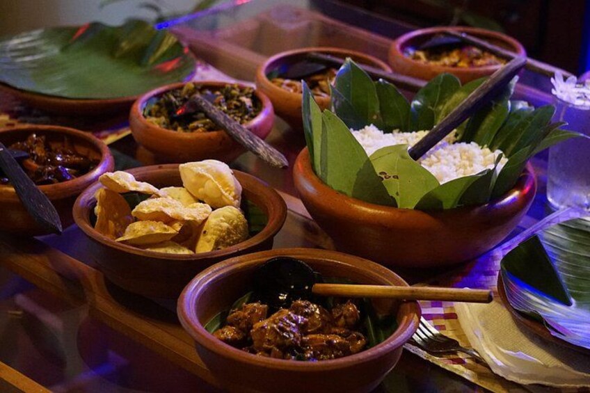 A variety of dishes in traditional clay bowls, some with leaves and a spoon. 3