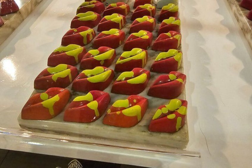 A tray of square-shaped pastries with red and yellow icing. 1