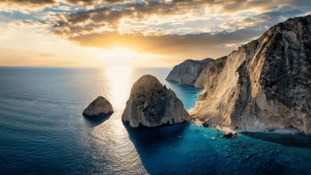 A coastal landscape with rocky cliffs and calm sea under a sunset sky. 1