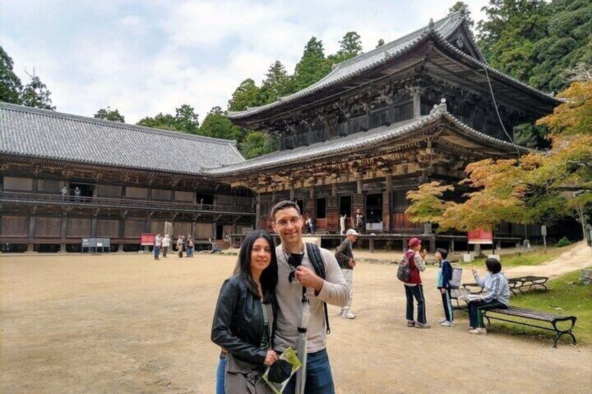 A traditional Japanese building with a tiled roof and wooden structure, surrounded by trees and a dirt path. 3