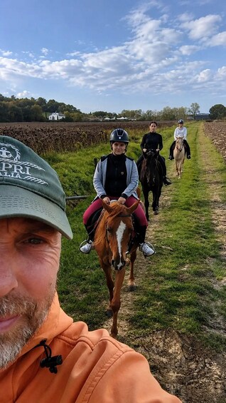 A person on a horse in a field with other riders in the background. 3