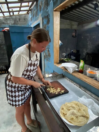 A person preparing food, chopping vegetables on a cutting board, with a tortilla on a baking sheet nearby. 3
