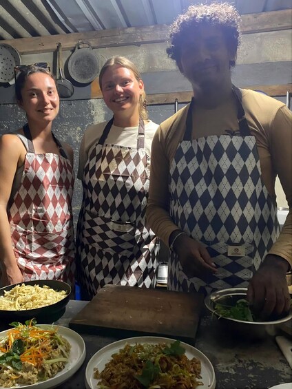 Three people in aprons preparing food in a kitchen. 2