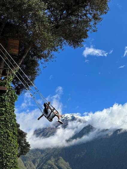 A person swinging on a rope over a mountainous landscape with clouds below. 2
