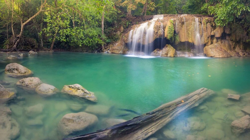 A waterfall cascading into a clear turquoise pool surrounded by rocks and lush greenery. 2