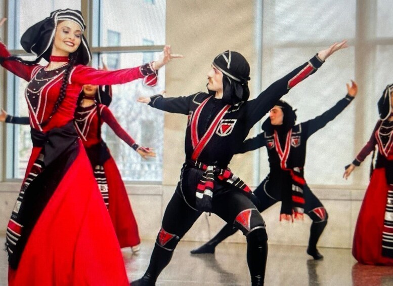 Dancers in red and black costumes performing in a studio with large windows. 3