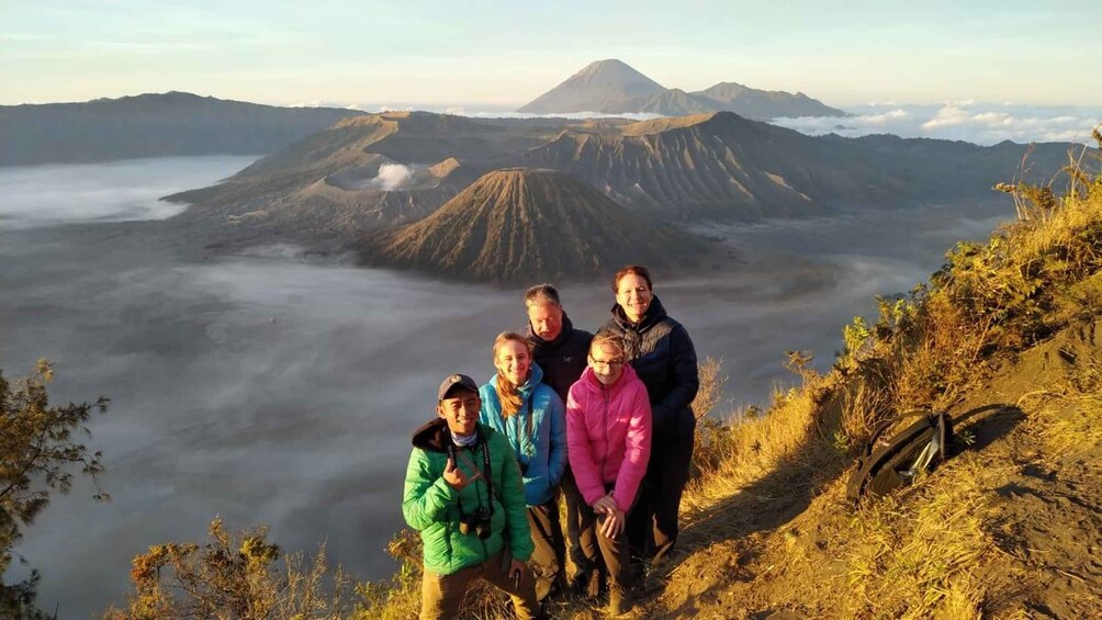 A group of people standing on a mountain ridge with a volcano in the background. 4