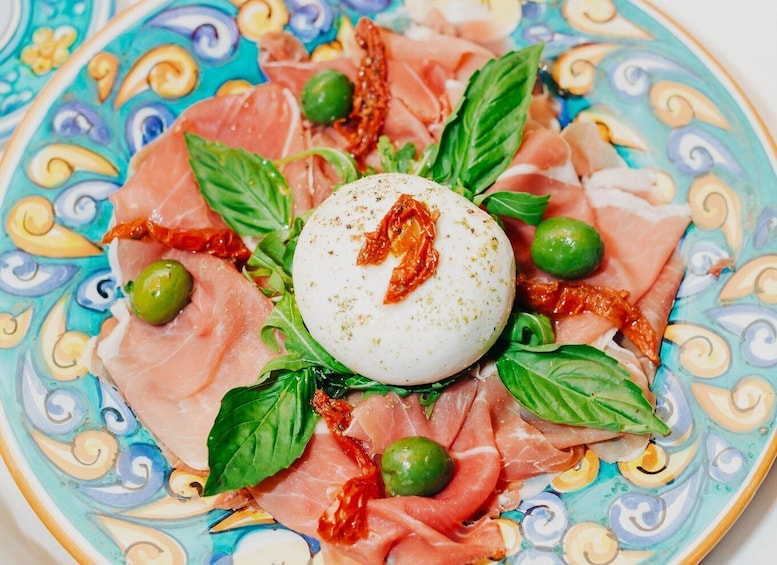 A plate of cured meats, a boiled egg, and green olives. 1