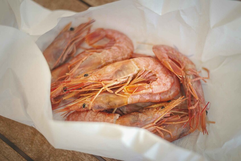 A pile of cooked shrimp in a white paper container. 3