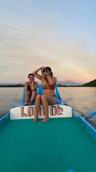 Three people on a boat with a 'LONDO' sign, taking a photo. 4