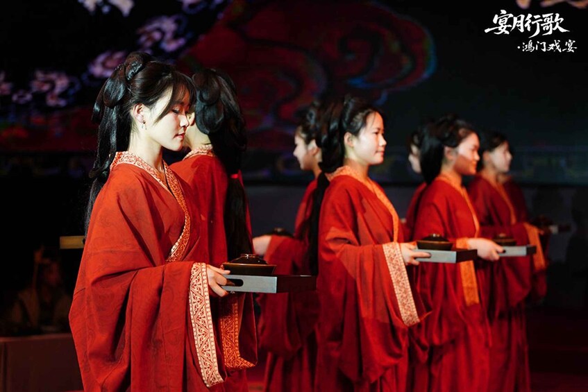 A group of people in traditional red attire holding trays, possibly at a cultural event. 3