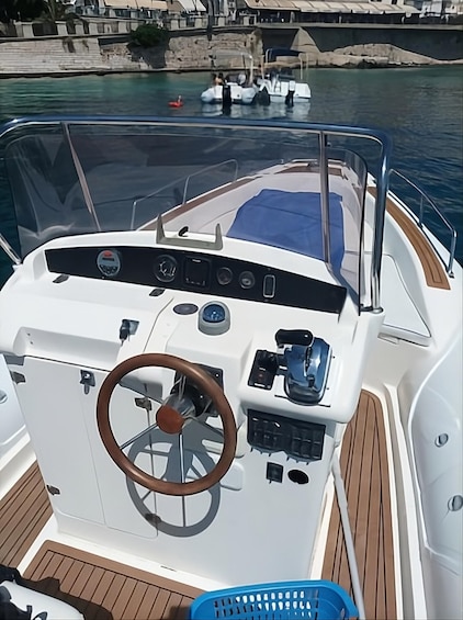 A boat's control station with a steering wheel, various gauges, and a blue cover. 5