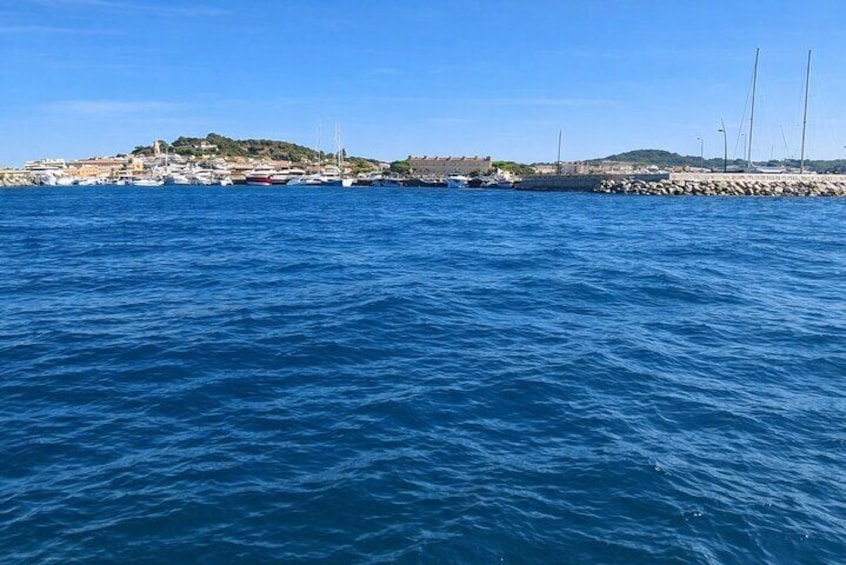 A coastal town with a clear blue sea, a rocky breakwater, and sailboats in the distance. 5
