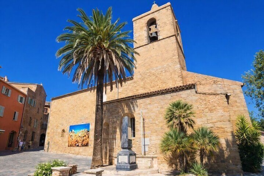 A historic stone church with a bell tower, palm trees, and a mural. 4