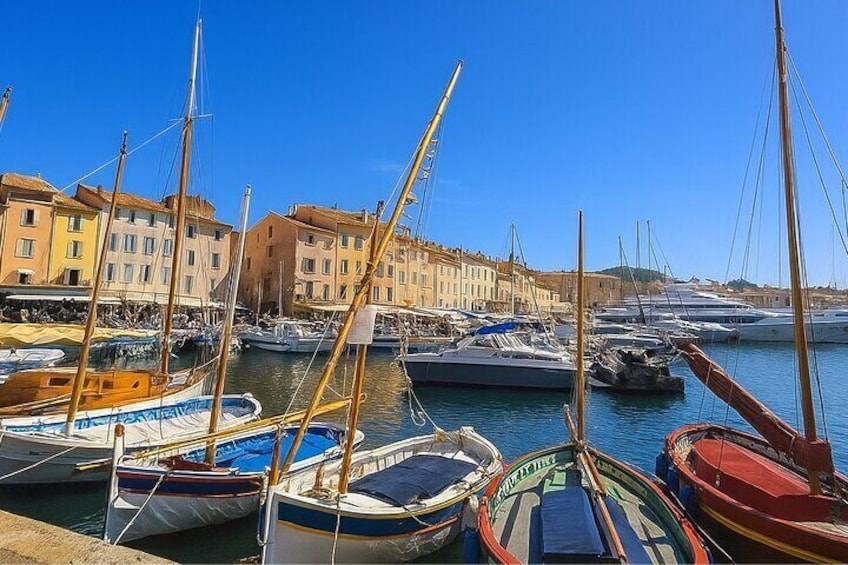 A marina with boats docked, buildings in the background, and clear blue skies. 3