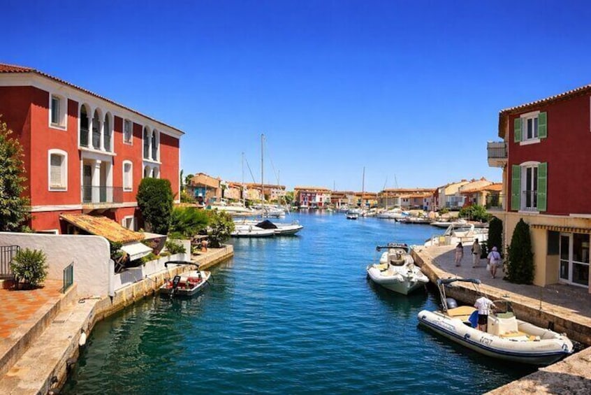 A canal with boats, red buildings, and clear blue sky. 2