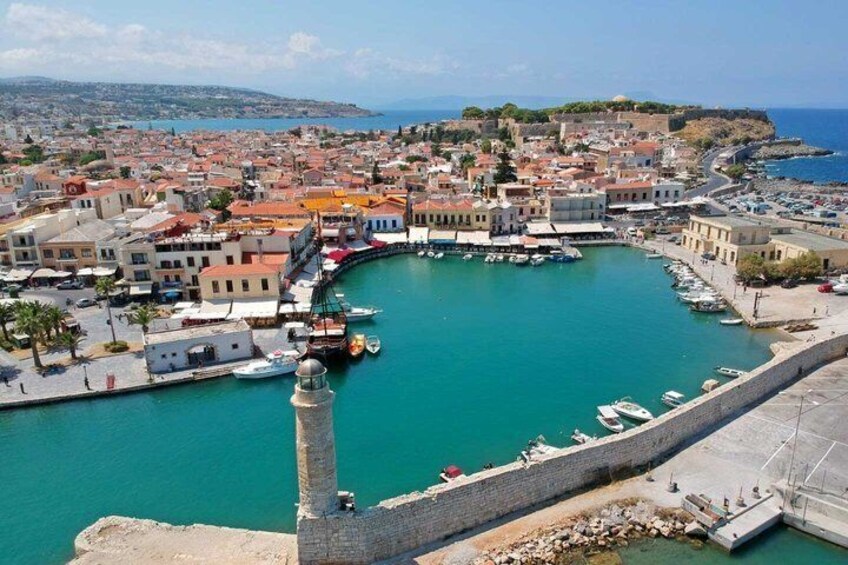 A coastal town with a prominent lighthouse, a harbor with boats, and a fortified hill in the background. 4