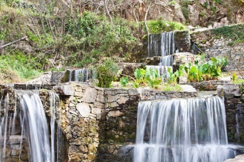 A multi-tiered stone waterfall with lush greenery around it. 3