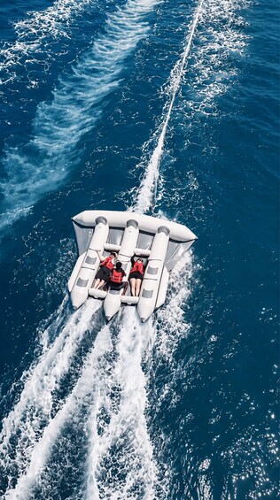 A speedboat with four people wearing life jackets, moving through the ocean. 3