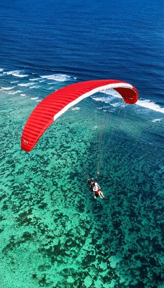 A person paragliding over clear blue ocean waters. 5