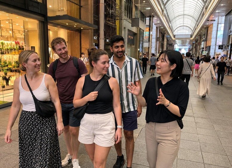 A group of people walking in a covered shopping mall with shops and a high ceiling. 4