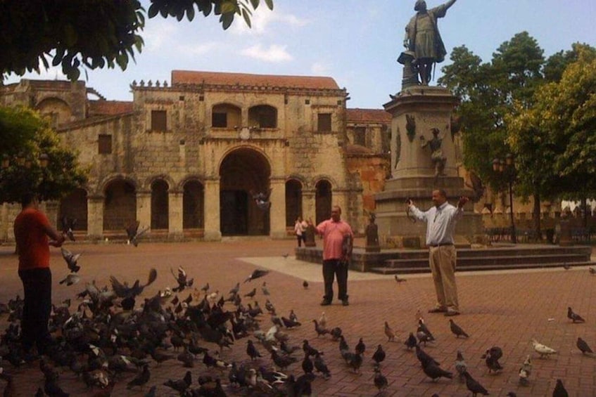 A historic building with arches, a statue, and pigeons. 3
