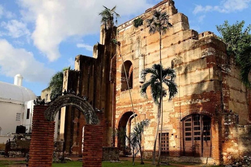 An ancient brick building with arches and palm trees. 1