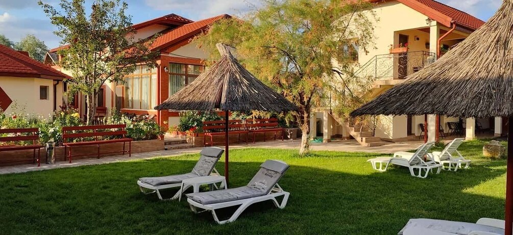A resort with thatched umbrellas, lounge chairs, and a well-maintained lawn. 3